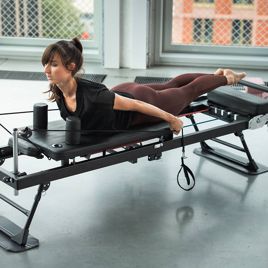 Vrouw traint op een Pilates-apparaat met weerstandsbanden.