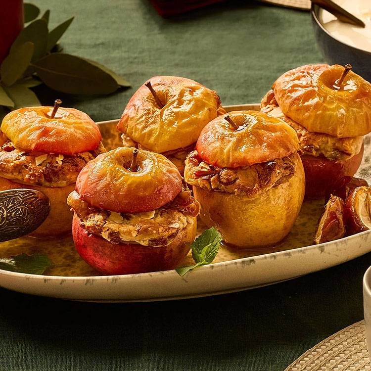 Gebakken appels gevuld met noten en kruiden, geserveerd op een schaal.