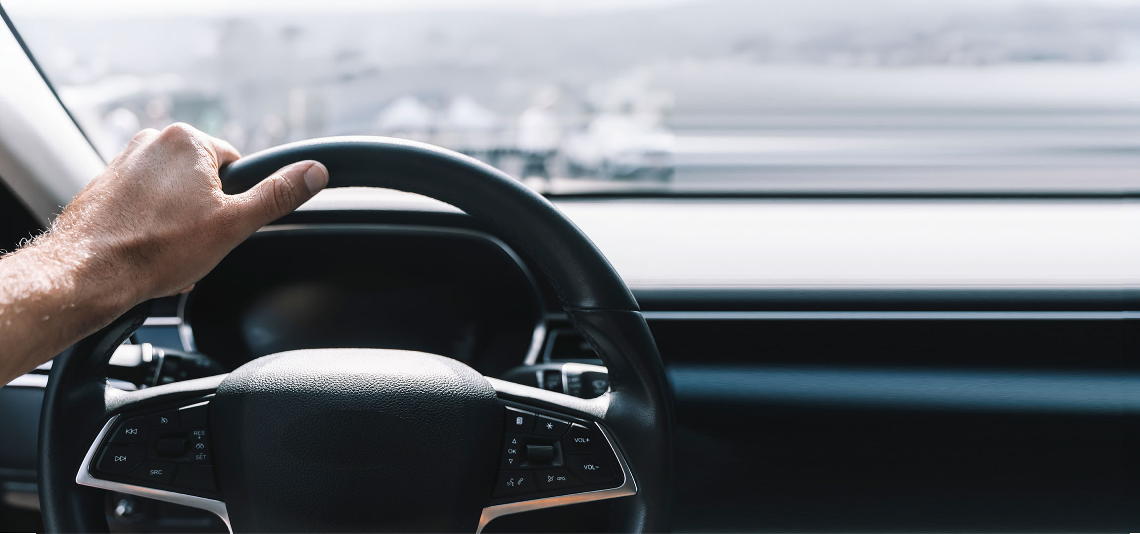 Mannenhand houdt het stuur van een auto vast.