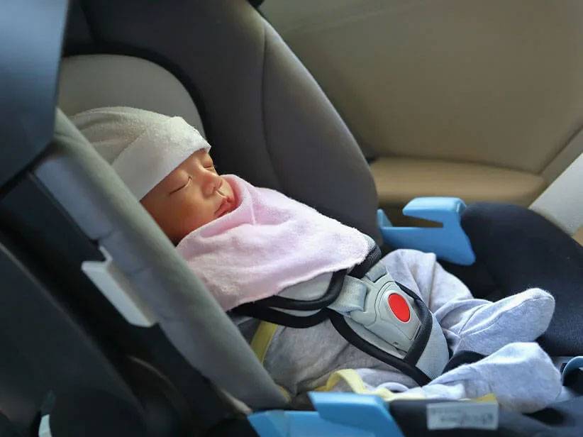 Baby slaapt in autostoeltje.