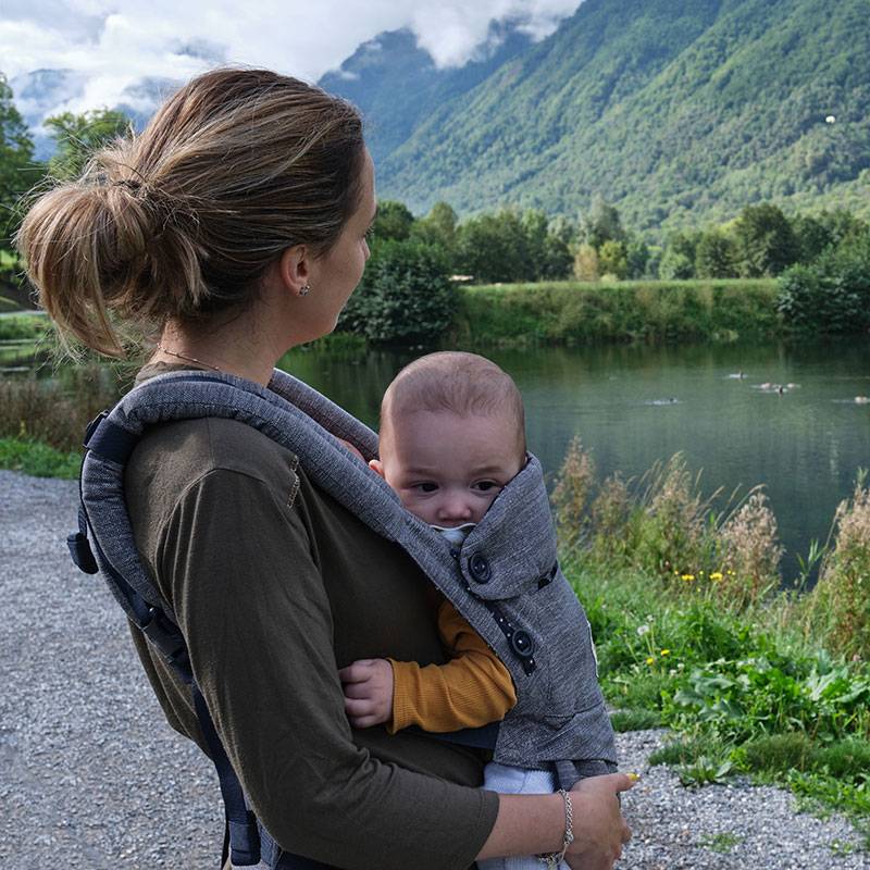 Moeder met baby in draagzak buiten.