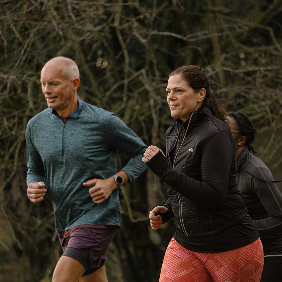Twee volwassen hardlopers in sportkleding joggen buiten.