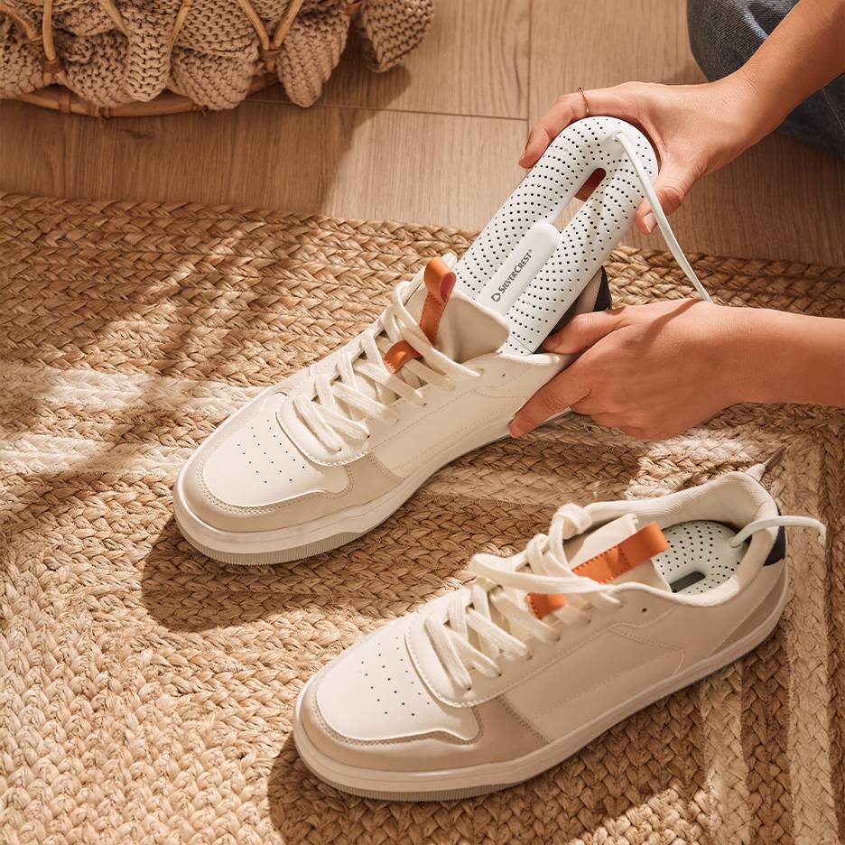 Silvercrest schoendroger in witte sneakers op een gevlochten vloerkleed.