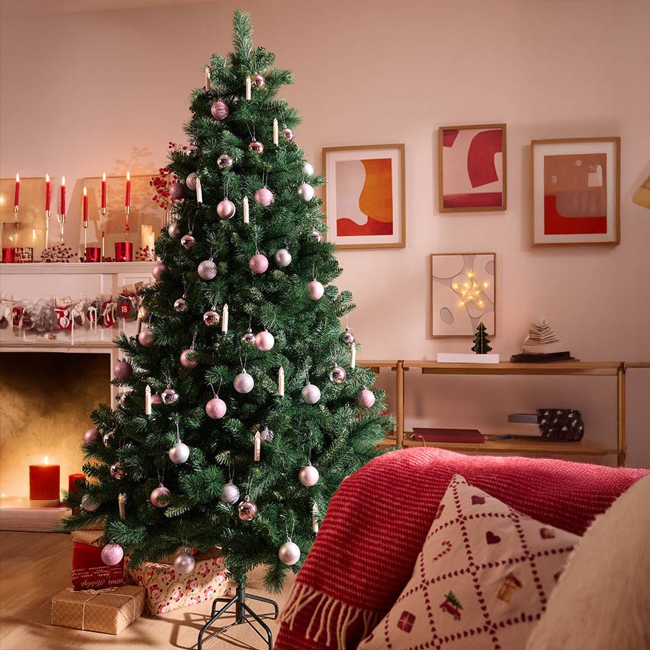 Kerstboom met roze en zilveren ballen in een gezellige woonkamer.