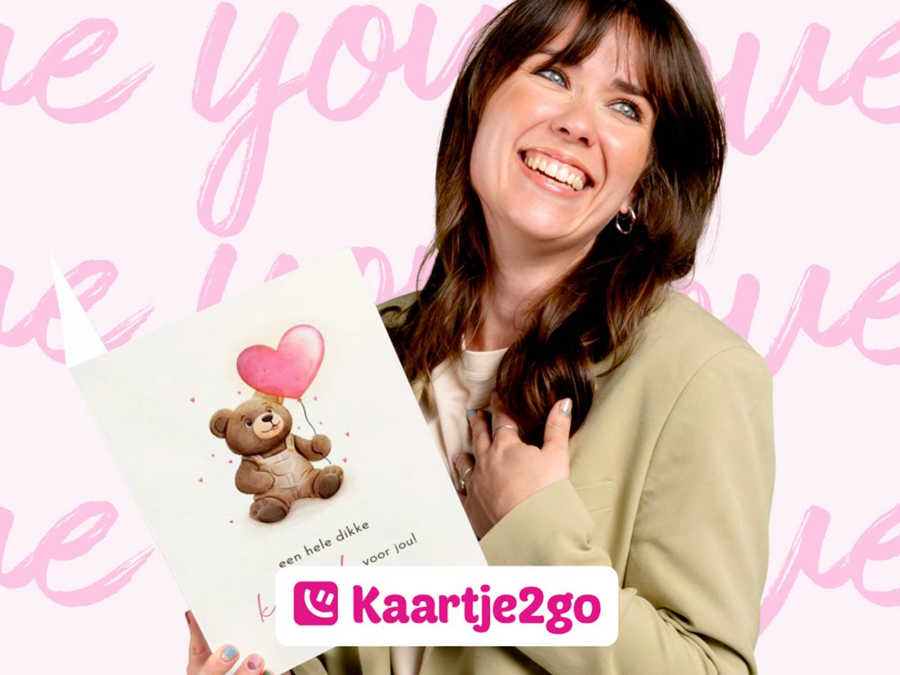 Vrolijke vrouw met een kaart met een teddybeer en een hartjesballon, op een roze achtergrond.