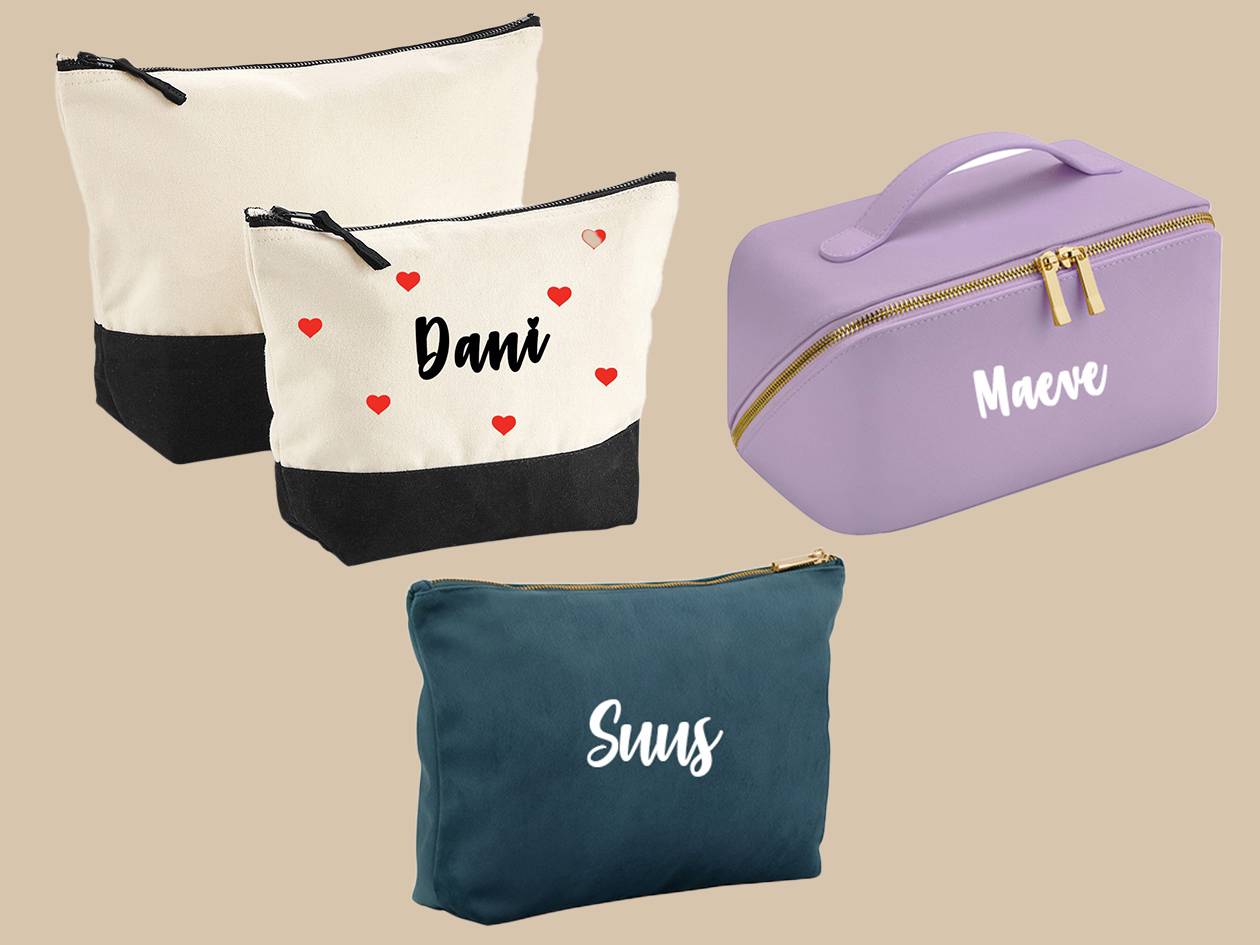 Drie gepersonaliseerde make-up tasjes: twee crèmekleurige met zwarte onderkant en rode hartjes, één paarse met handvat, en één donkerblauw.