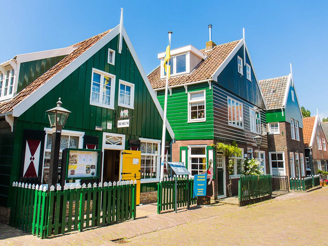 Rij kleurrijke, traditionele houten huizen in een Dutch dorp, waarvan één een museum is.