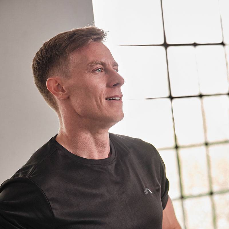 Een man in een zwart t-shirt kijkt weg naar een raam.