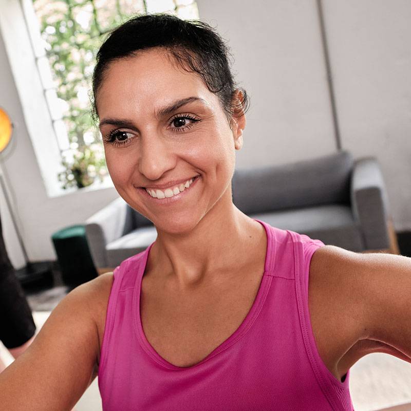 Lachende vrouw in roze top sport thuis.