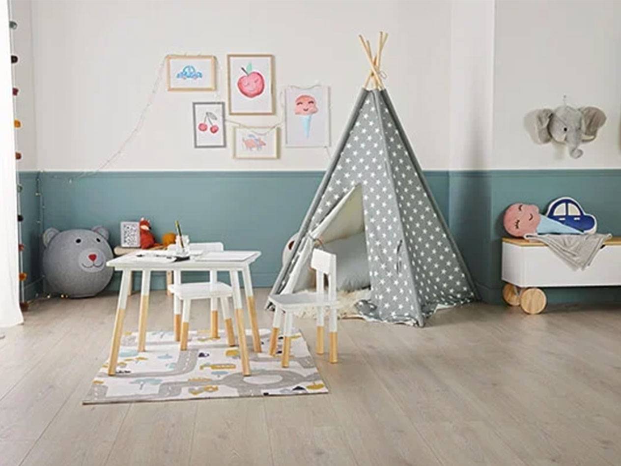 Kinderkamer met tipi-tent, tafel en stoelen, speelgoedkist en schilderijen aan de muur.