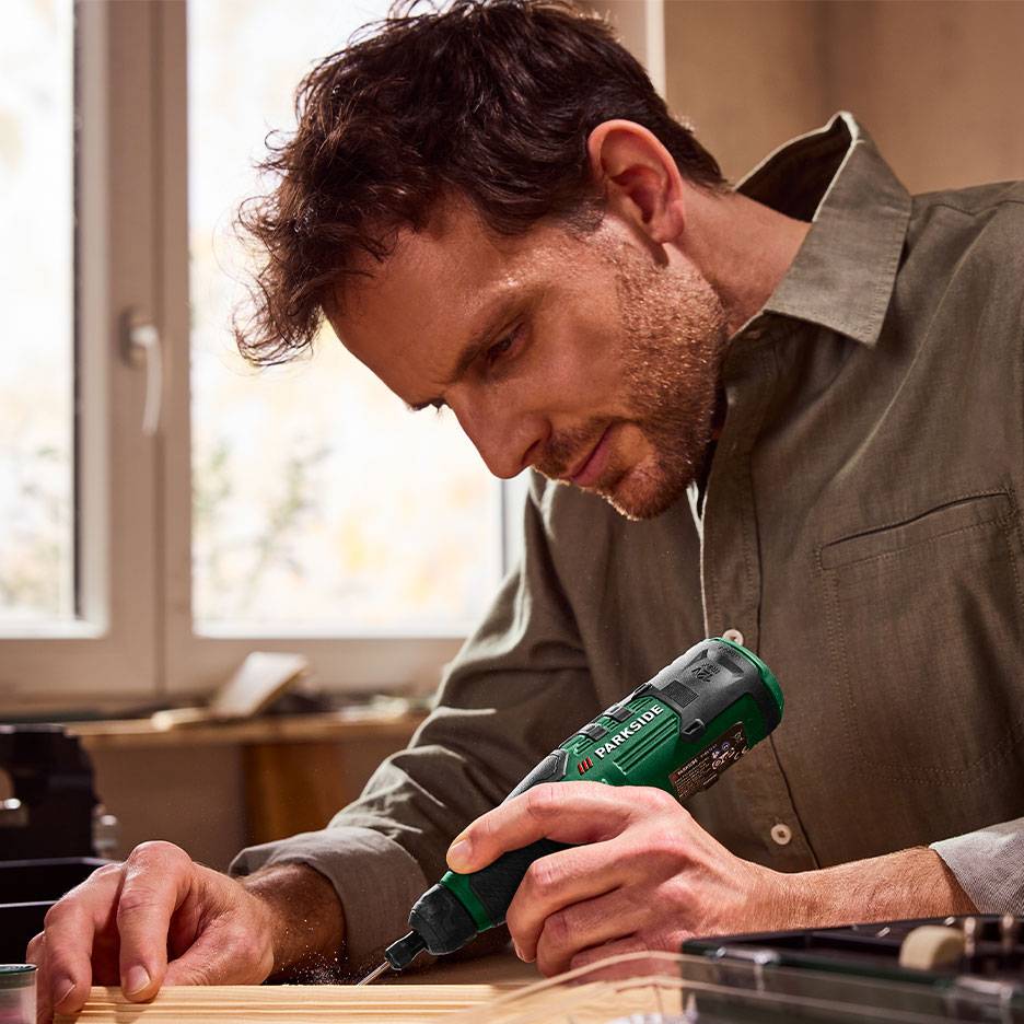 Man gebruikt een groene elektrische schroevendraaier voor houtbewerking.