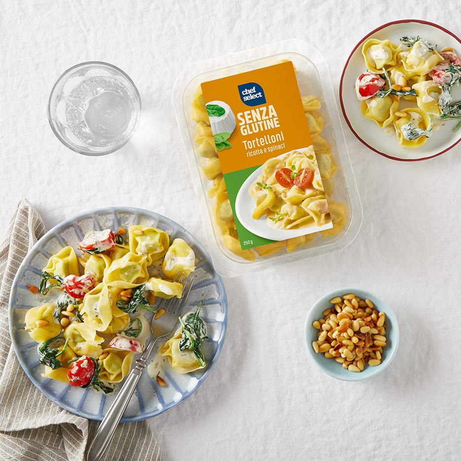 Chef Select glutenvrije tortelloni met ricotta en spinazie, geserveerd met pijnboompitten en water.