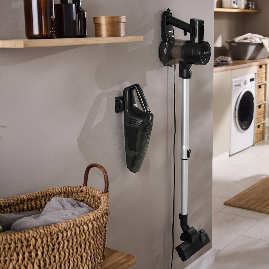 Twee zwarte Silvercrest stofzuigers aan de muur in een wasruimte met een wasmachine.