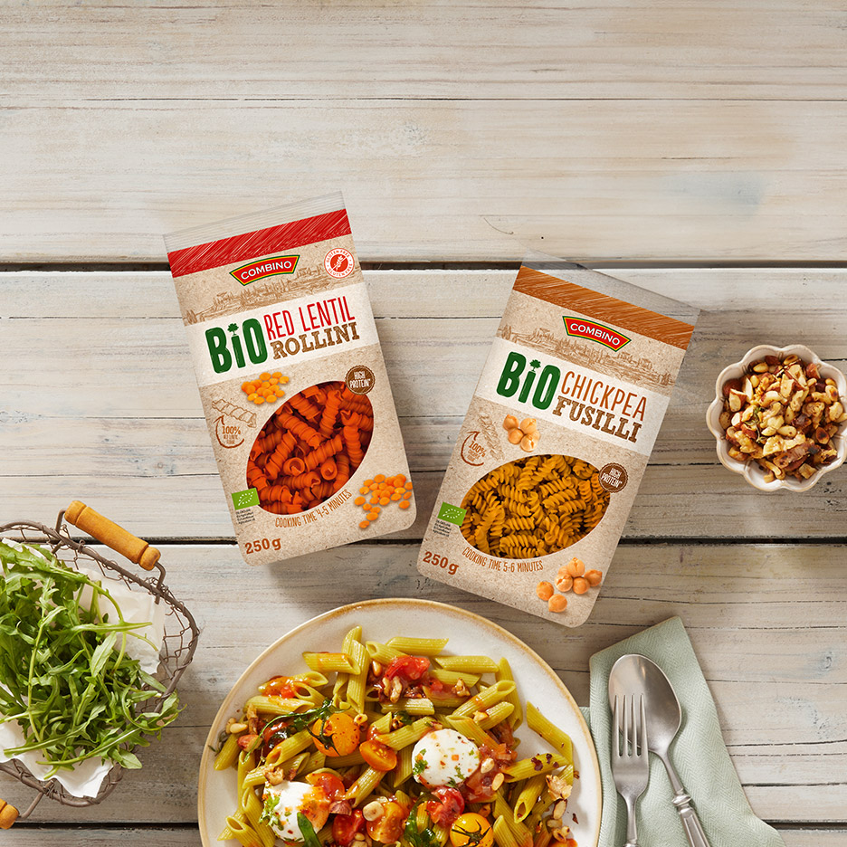 Twee zakjes biologische pasta van rode linzen en kikkererwten, met een pastagerecht en rucola.