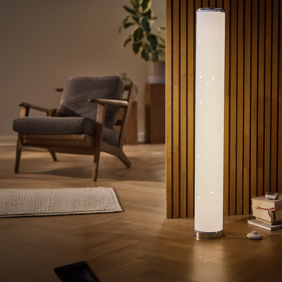 Staande lamp met sterrenpatroon in een woonkamer met fauteuil en plant.