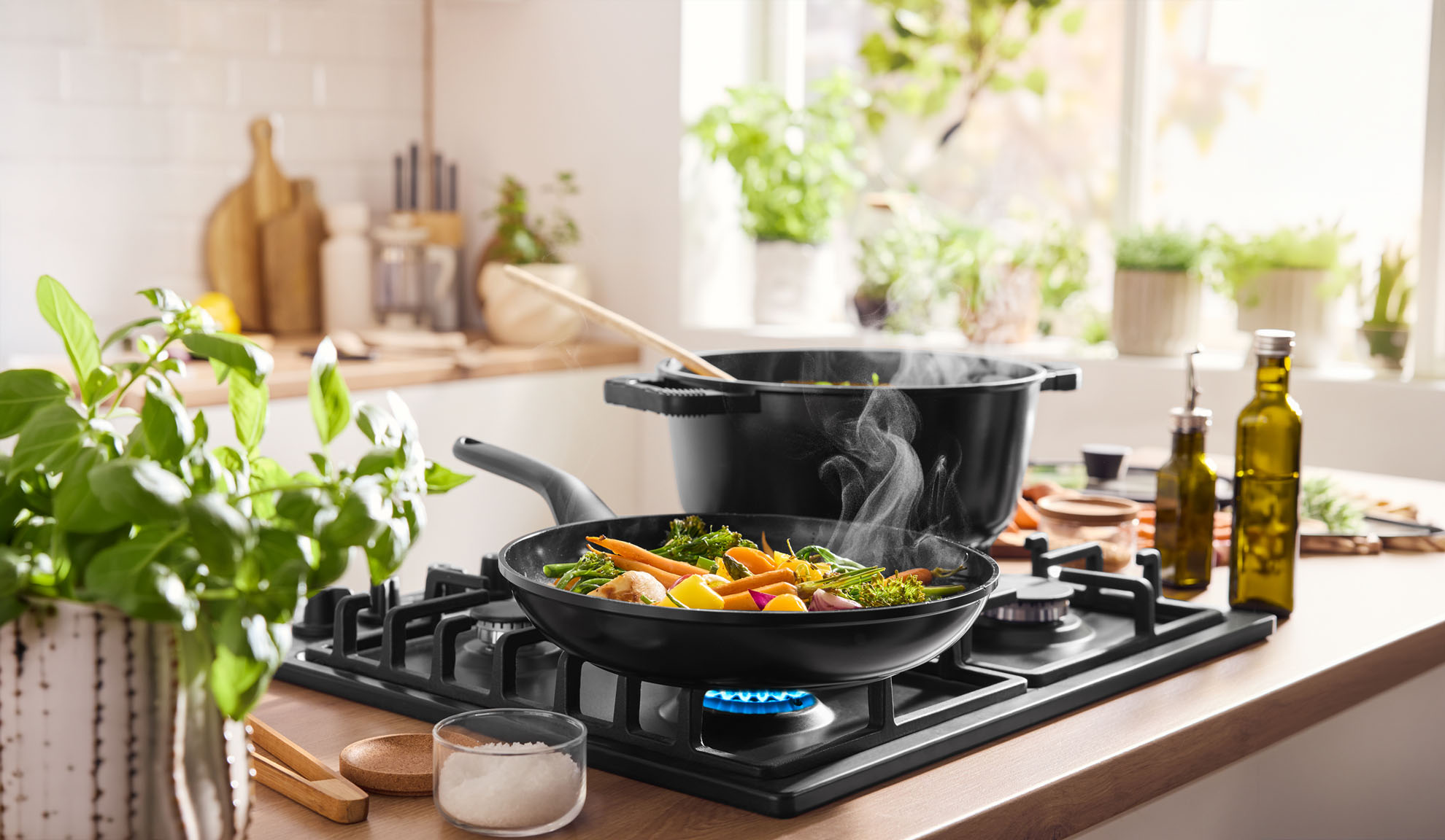 Stoomende groenten koken in pan en pot op een gasfornuis in een lichte keuken.