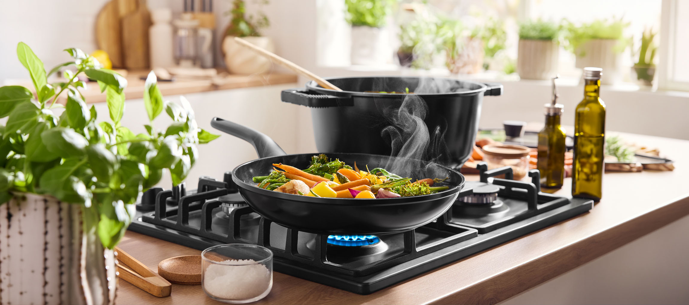 Groenten koken in een pan op een gasfornuis, met een pot en olijfolie in de buurt.