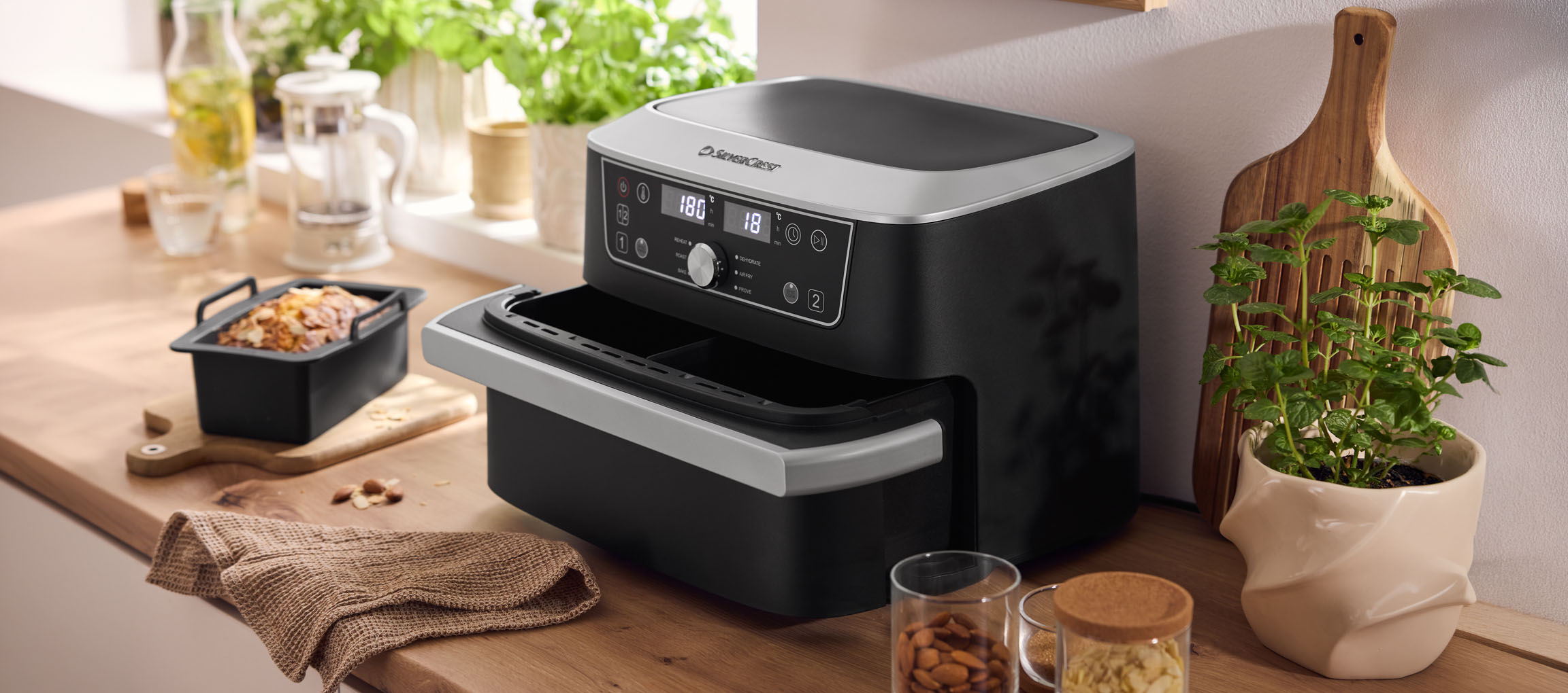 Zwarte airfryer met dubbele oven en gebak op een houten aanrecht.