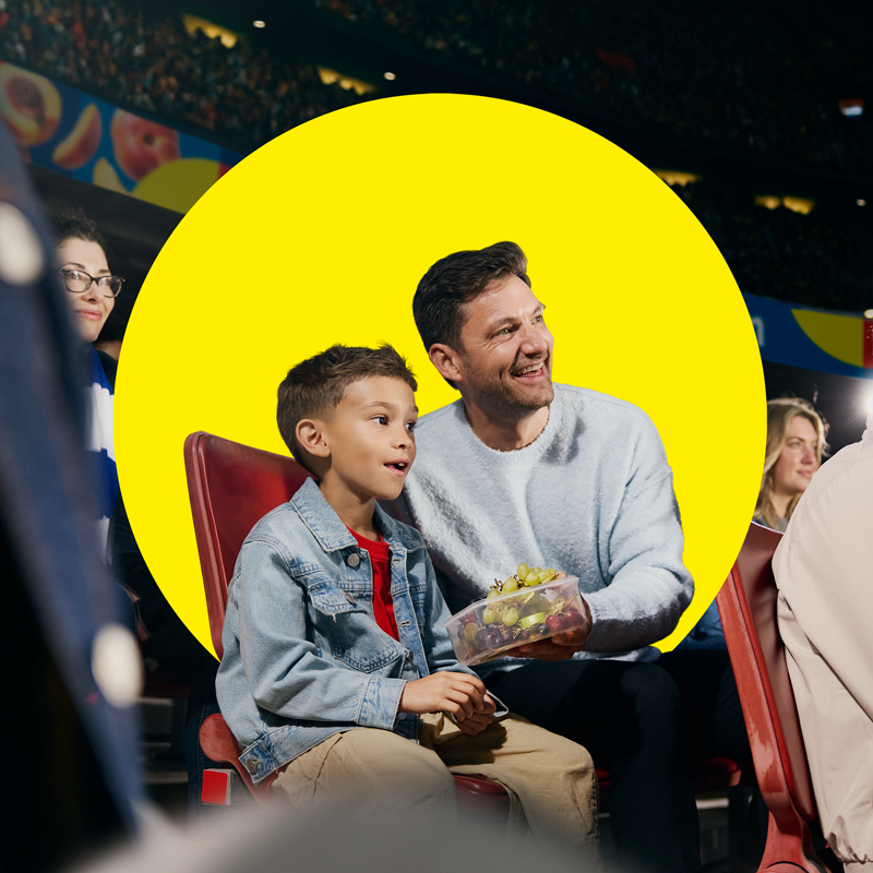 Vader en zoon genieten van fruit in een bakje tijdens een sportevenement.