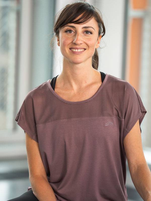 Lachende vrouw draagt een paarse sporttop met korte mouwen.