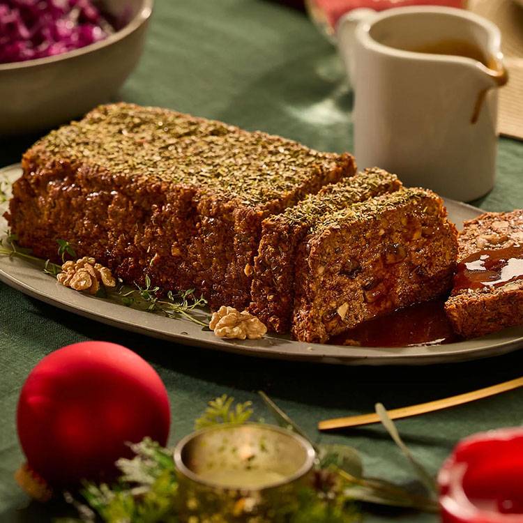 Hartig notenbrood met kruiden, walnoten en saus, geserveerd op een feestelijke tafel.
