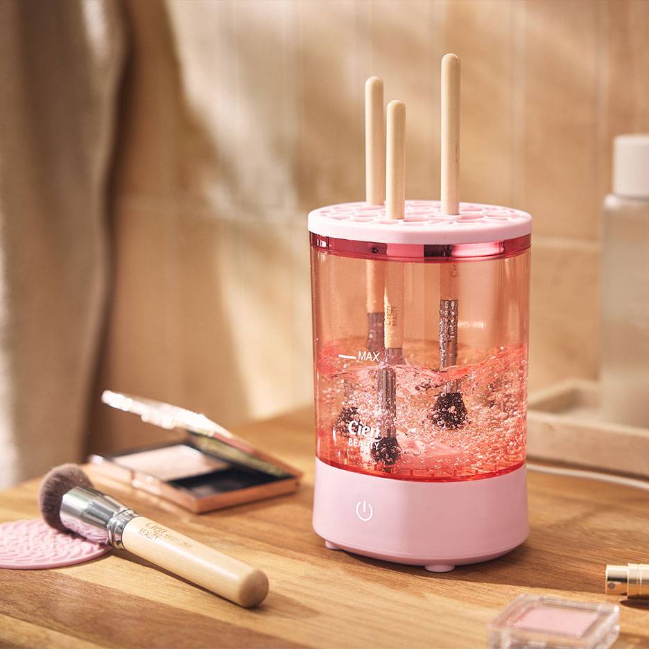 Roze make-upkwastenreiniger met kwasten in schuimend water.