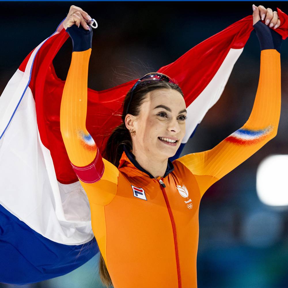 Vrouwelijke schaatser in oranje pak viert overwinning met Dutche vlag