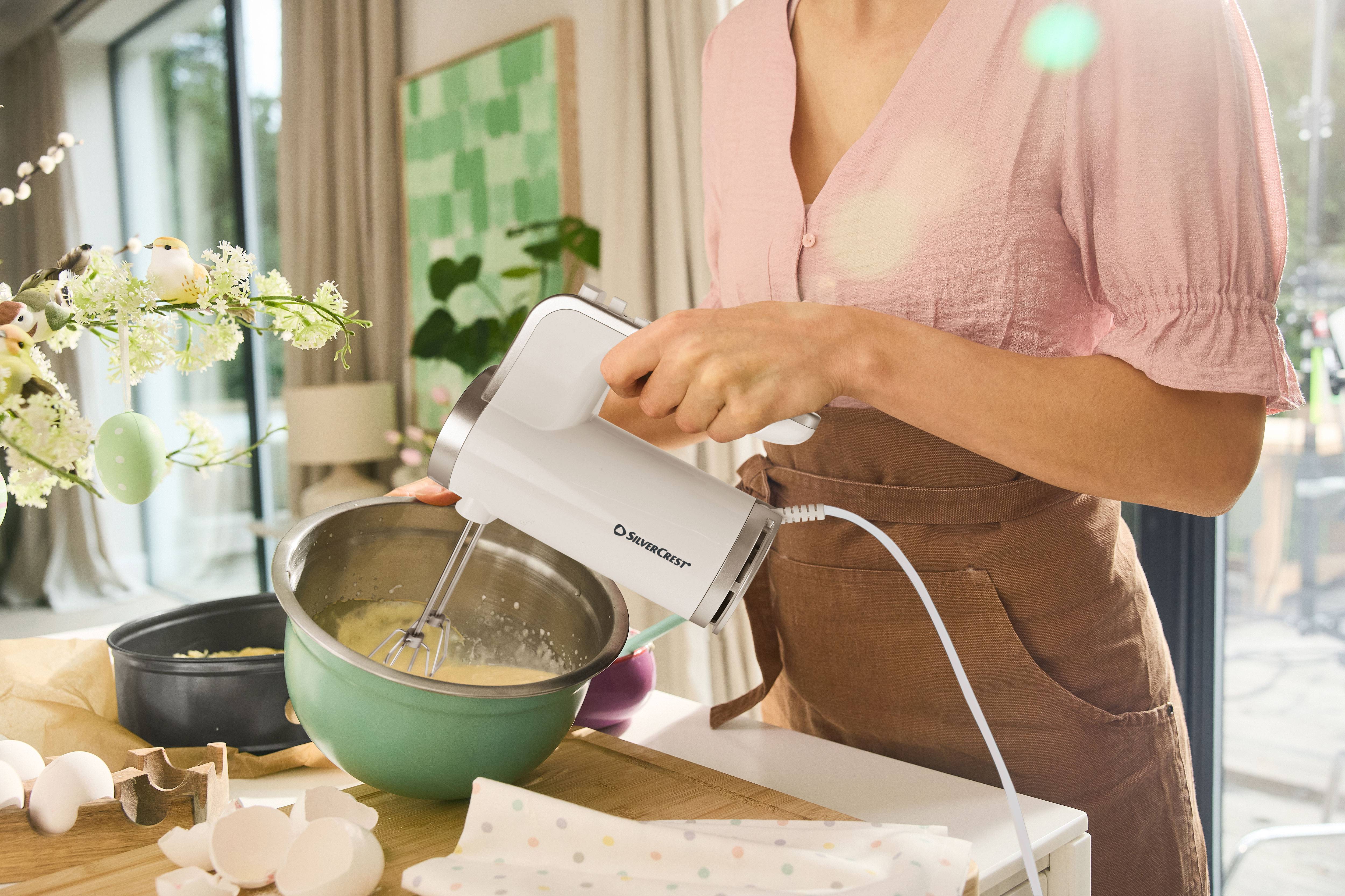 Vrouw gebruikt een SilverCrest handmixer om ingrediënten in een kom te mengen.