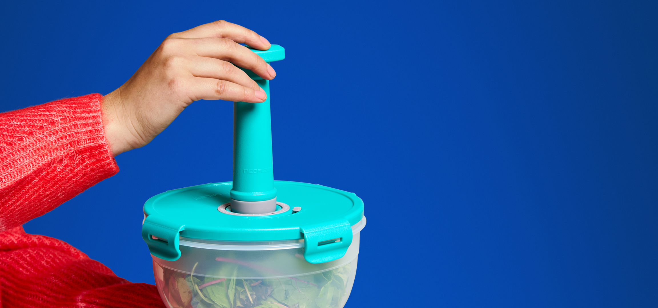 Een persoon in een rode trui houdt een turquoise en transparante beker vast.