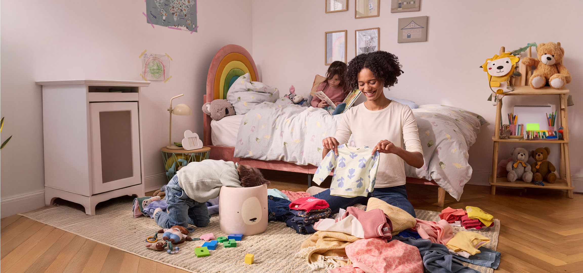 Een moeder ruimt kinderkleding op in een kinderkamer.
