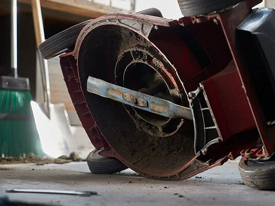 Vuile grasmaaier ondersteboven, mes zichtbaar