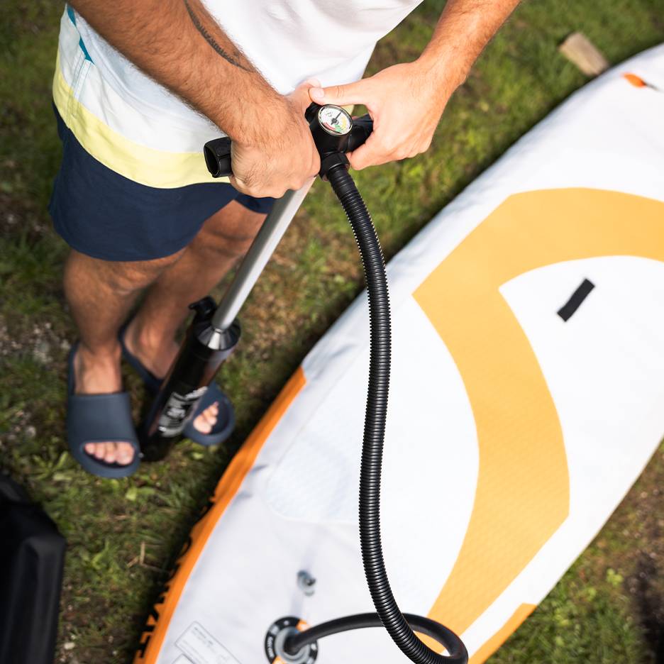 Man pompt een opblaasbaar paddleboard op met een handpomp.