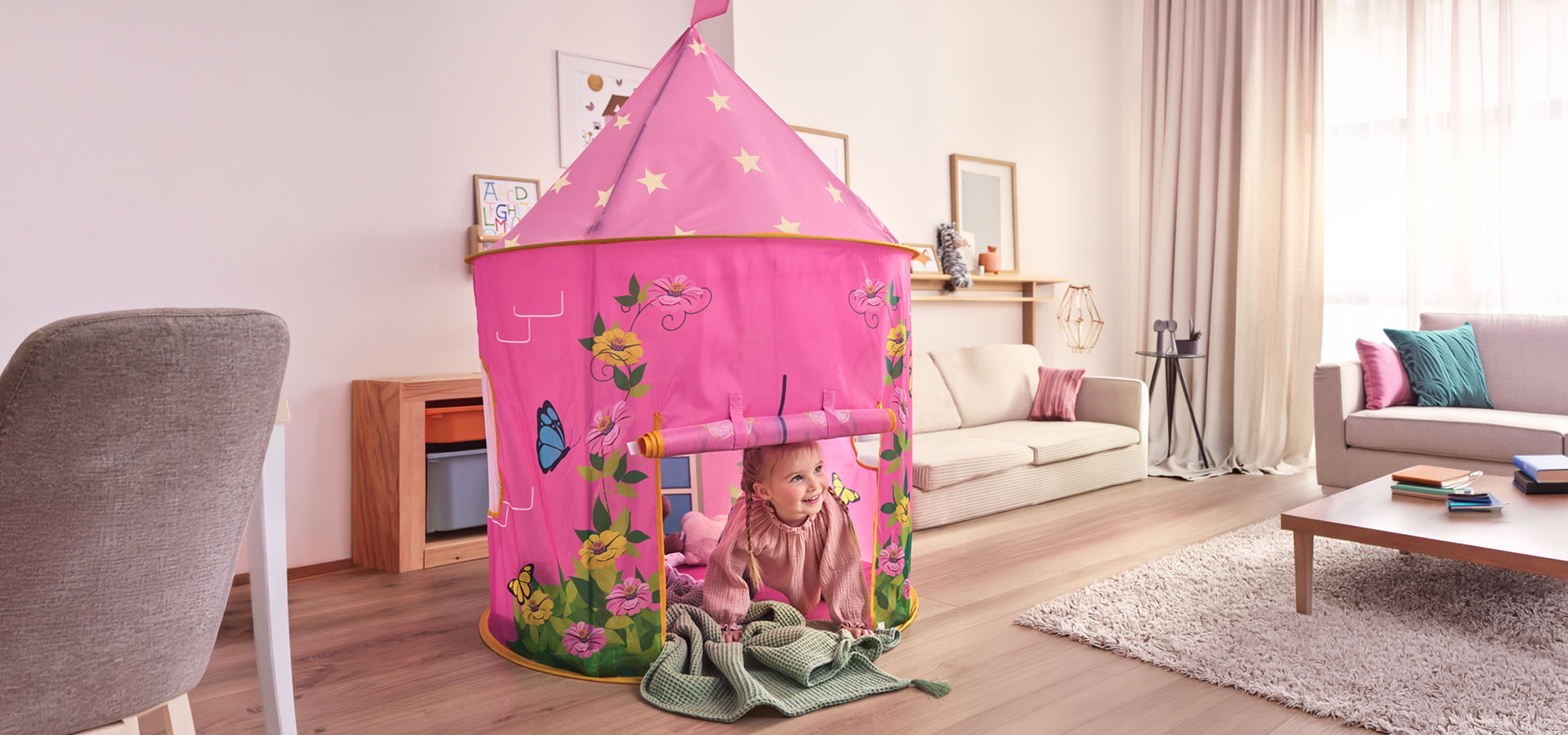 Roze kinderspeeltent in de vorm van een kasteel in een woonkamer met eethoek.
