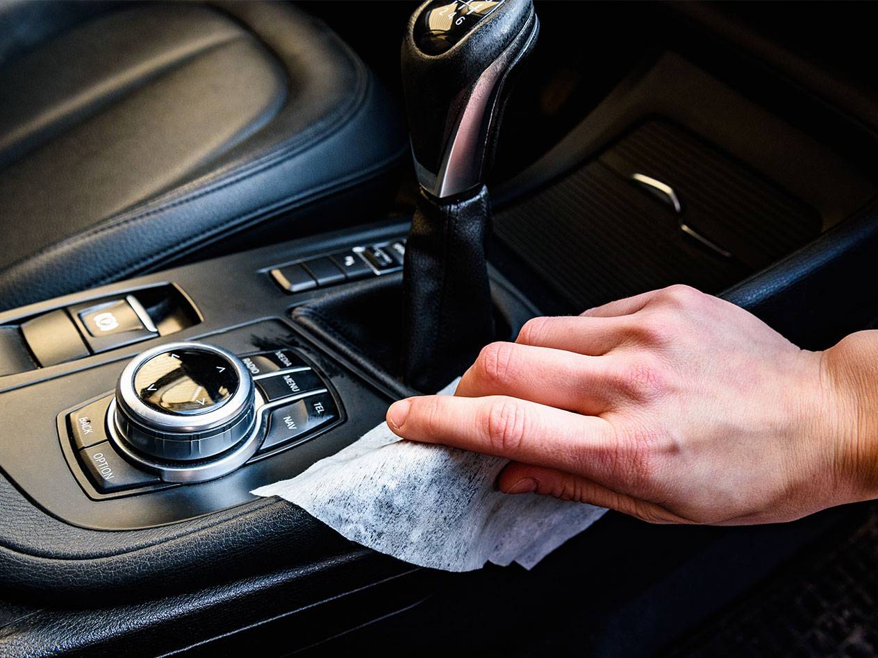 Hand reinigt auto-interieur met een vochtig doekje.