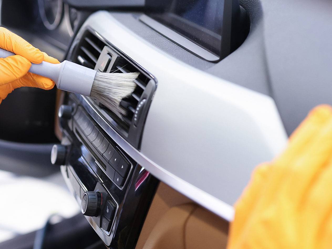 Auto-interieur reinigen met een detailborstel en rubberen handschoenen.
