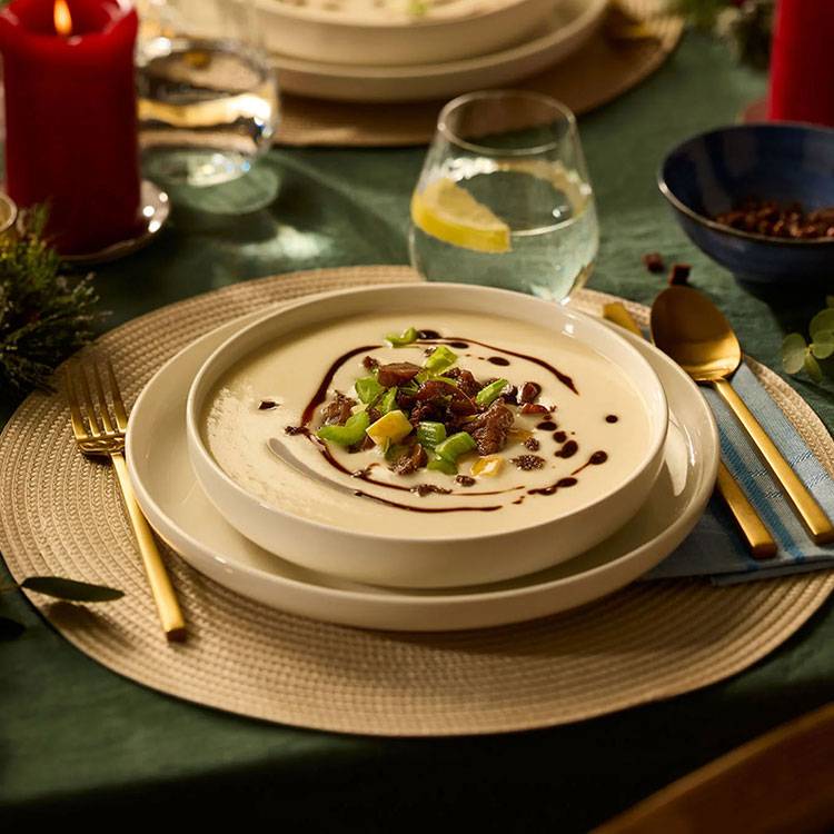 Romige soep met toppings, geserveerd op een feestelijk gedekte tafel.