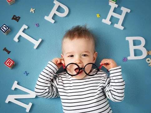 Baby met bril en houten letters.