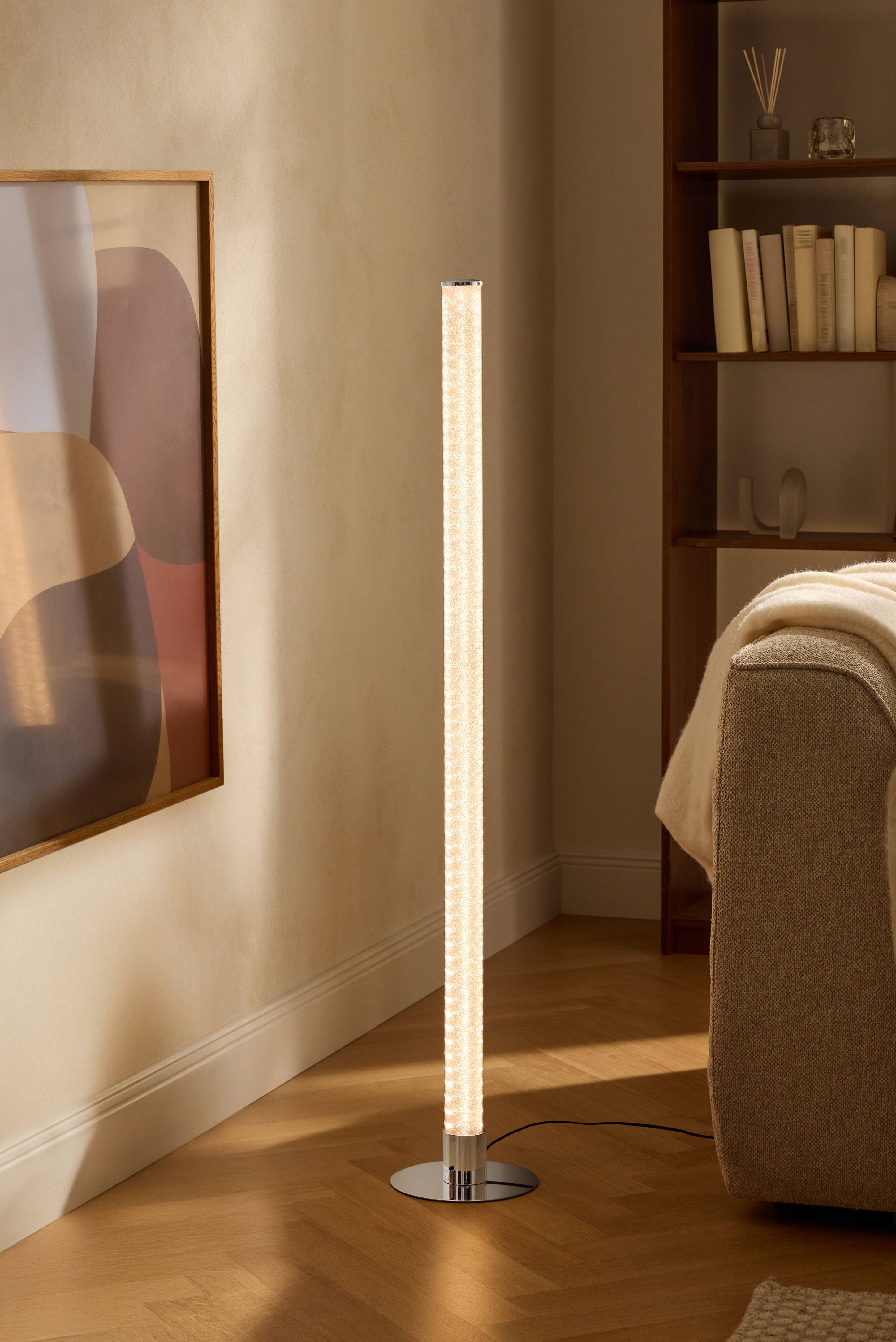 Moderne vloerlamp in woonkamer met boekenplank en bank.