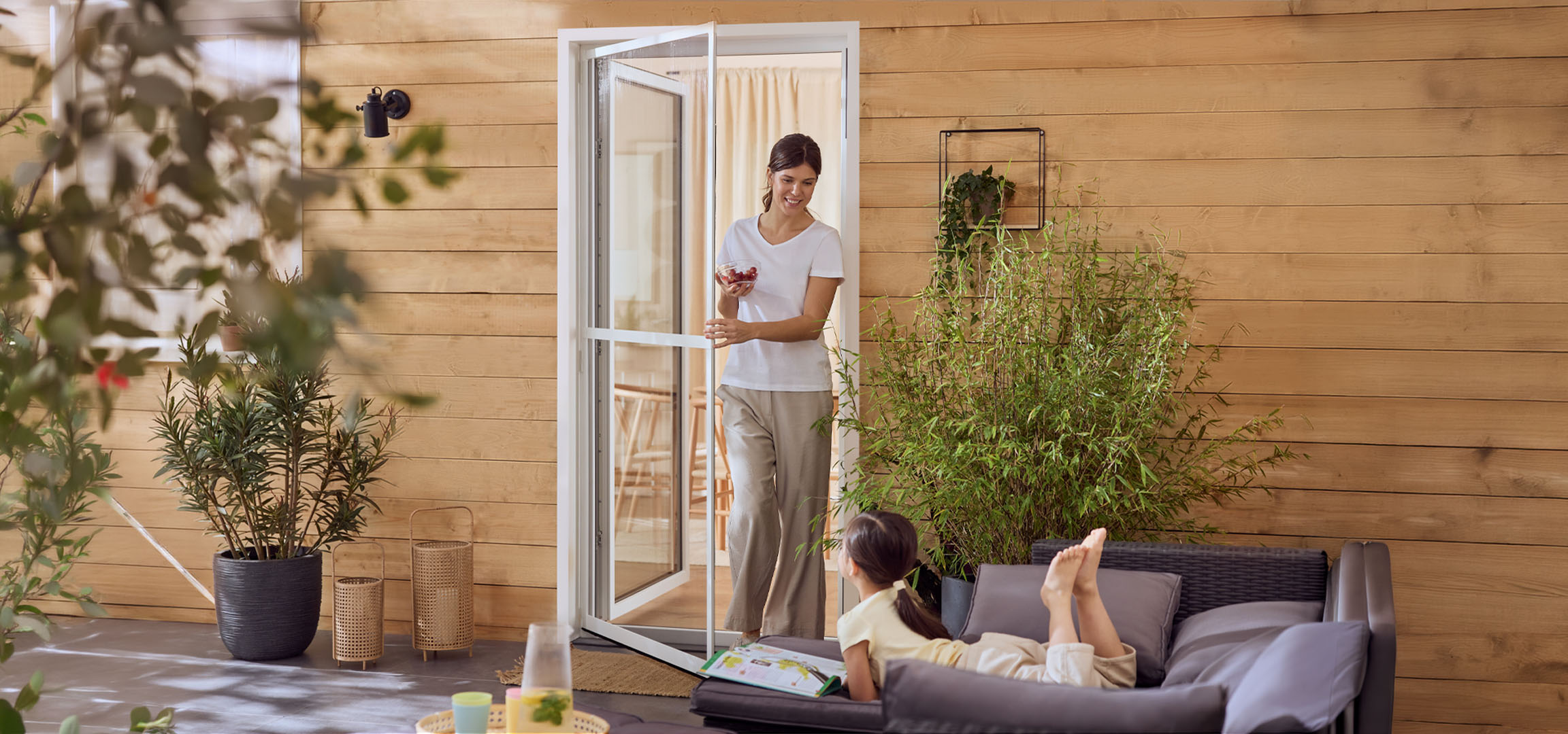 Vrouw en meisje genieten van een terras met tuinmeubelen en planten.