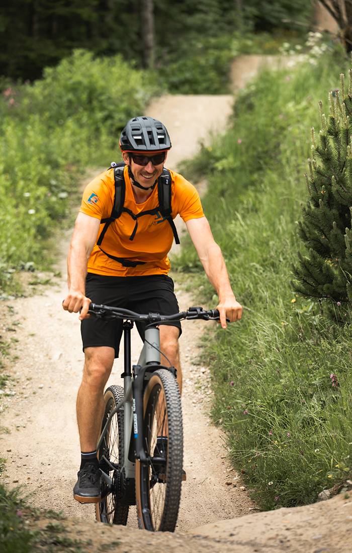 Een man lacht terwijl hij mountainbike op een pad.