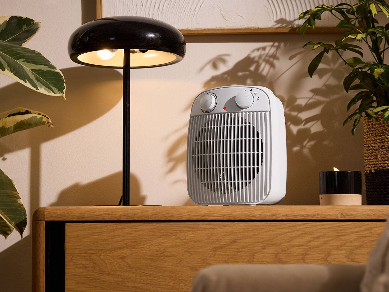 Witte kachel en zwarte tafellamp op een houten meubel in een gezellige kamer.