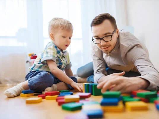 Vader en zoon spelen met houten blokken.