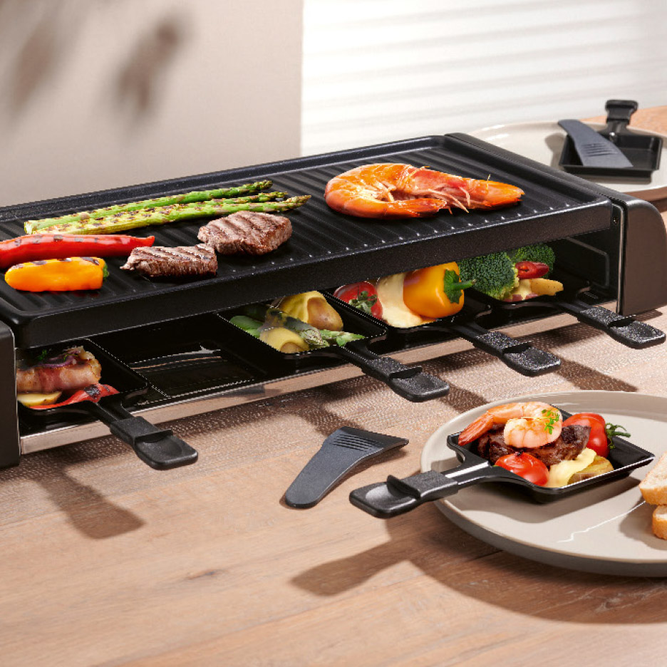 Raclette grill met vlees, garnalen en groenten op een houten tafel