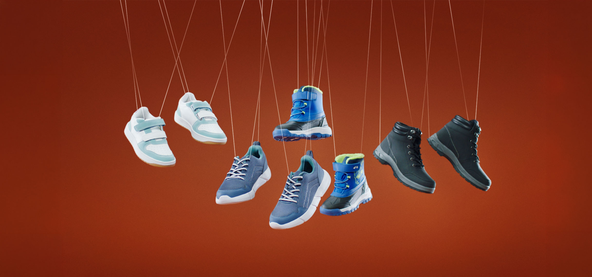 Diverse kinderschoenen, waaronder sneakers en laarzen, hangend aan touwtjes.