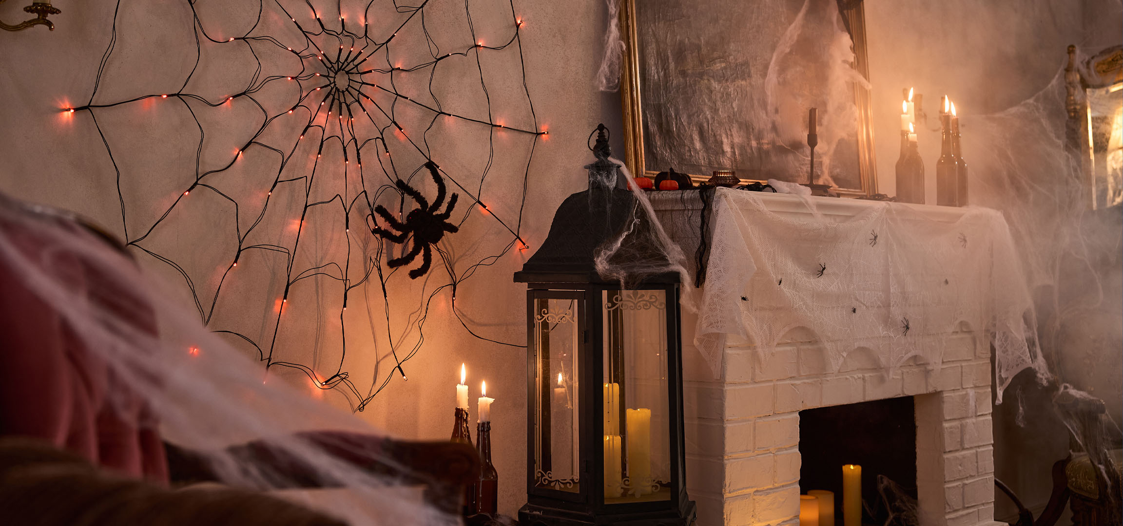 Halloween decoraties met spinnenwebverlichting, een grote spin en kaarsen.