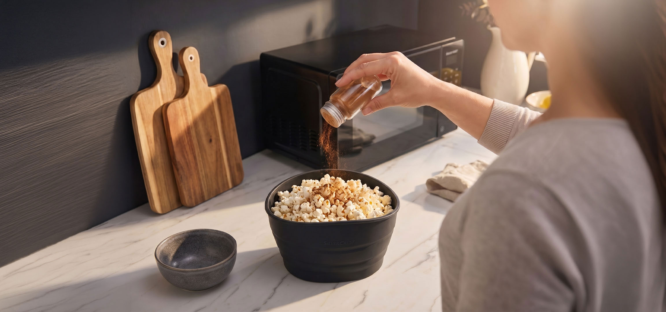 Gegenereerd door AI: Popcorn in een zwarte kom gekruid met specerijen, naast houten snijplanken.