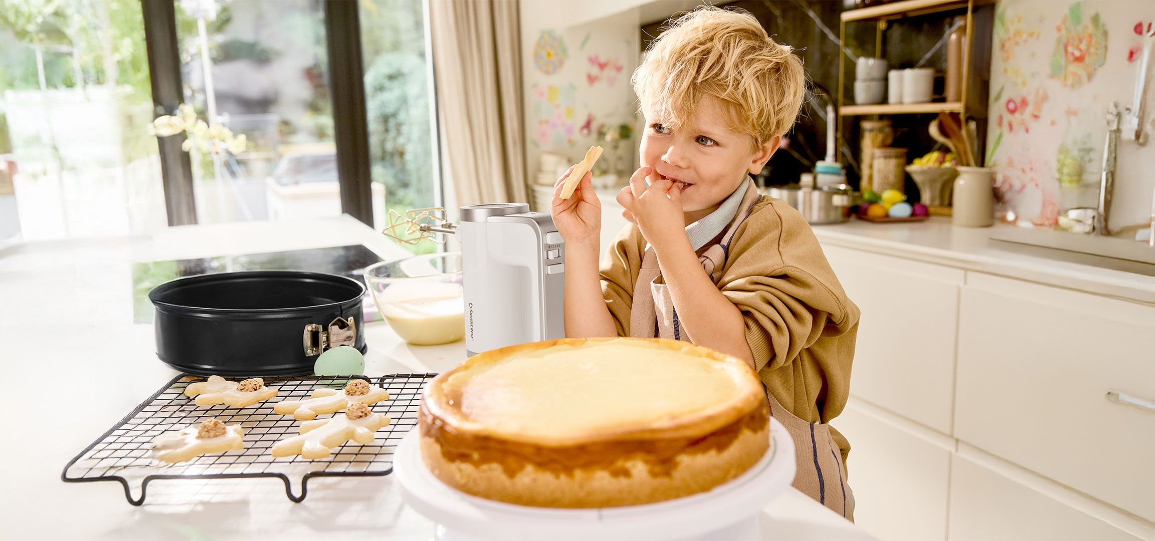 Jongen proeft beslag tijdens het bakken van taart en koekjes in de keuken.