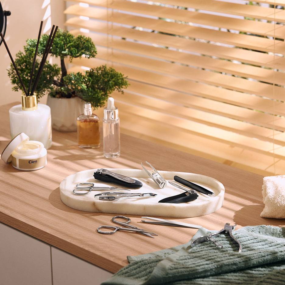 Manicureset op marmeren dienblad, met cosmetica en planten op houten oppervlak.
