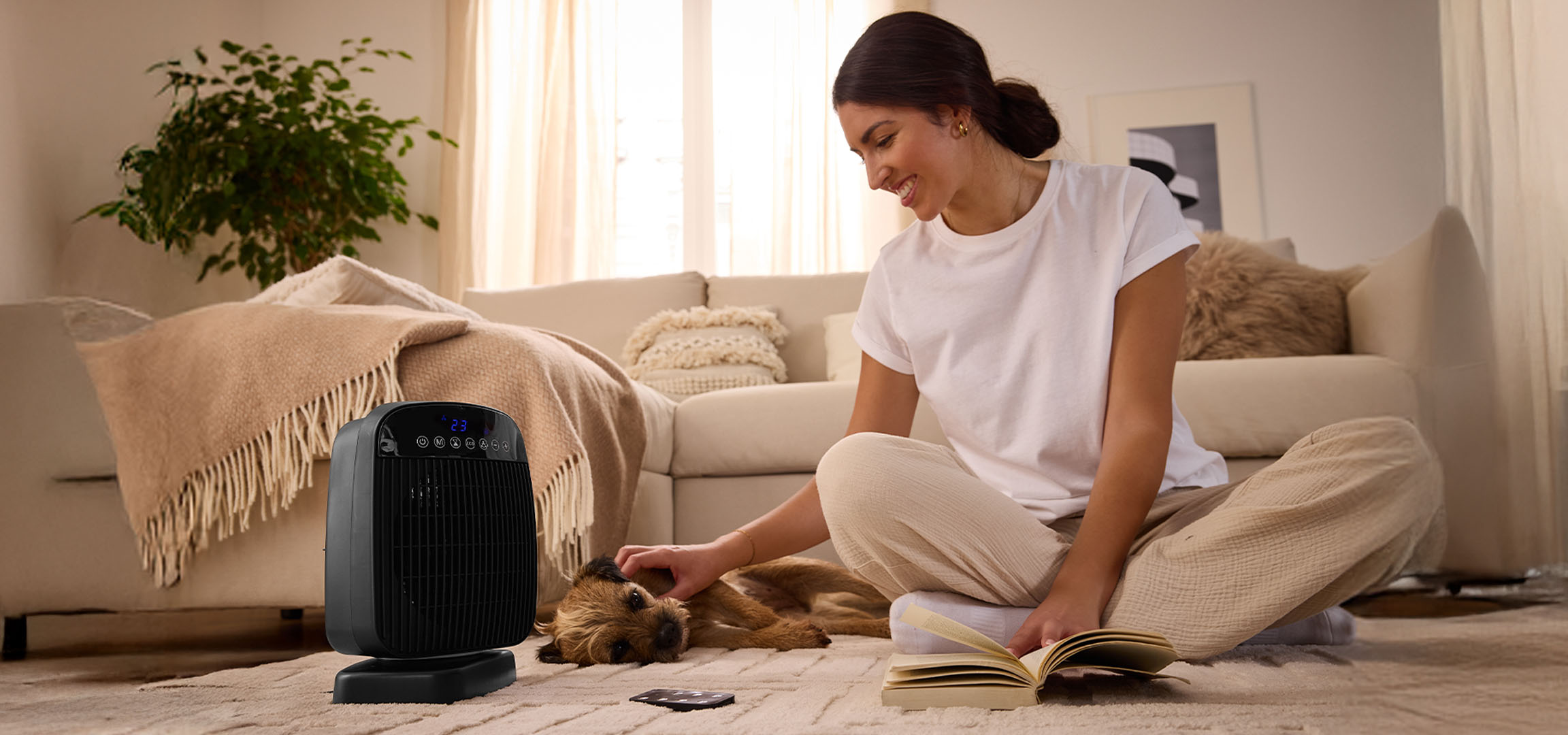 Een vrouw speelt met een hond naast een elektrische kachel in een woonkamer.
