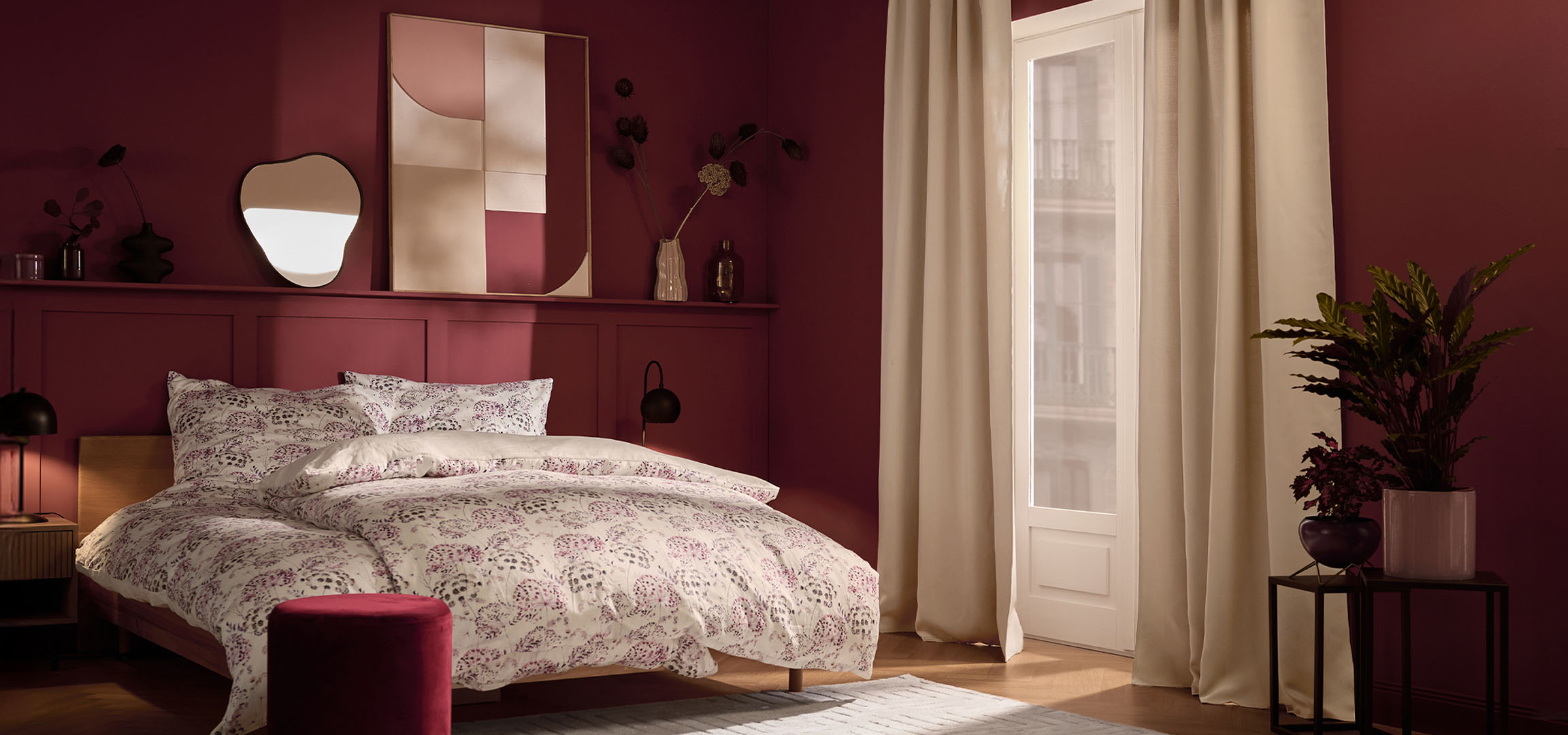 Slaapkamer met bordeauxrode muren, bed met wit bloemenbeddengoed en planten.